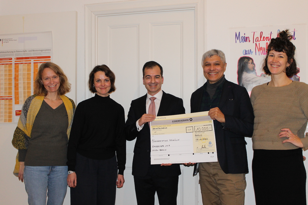 5 Personen, 3 Frauen und 2Männer, stehen nebeneinander. Die beiden Männer halten einen Spendenscheck über 10.000 Euro ins Bild.