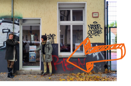 Eingang mit Pfeil Foto von Büro von "Leicht gemacht" von außen. Zwei Leute zeigen auf die Eingangstür. Ein oranger Pfeil zeigt auch auf die Eingangstür.